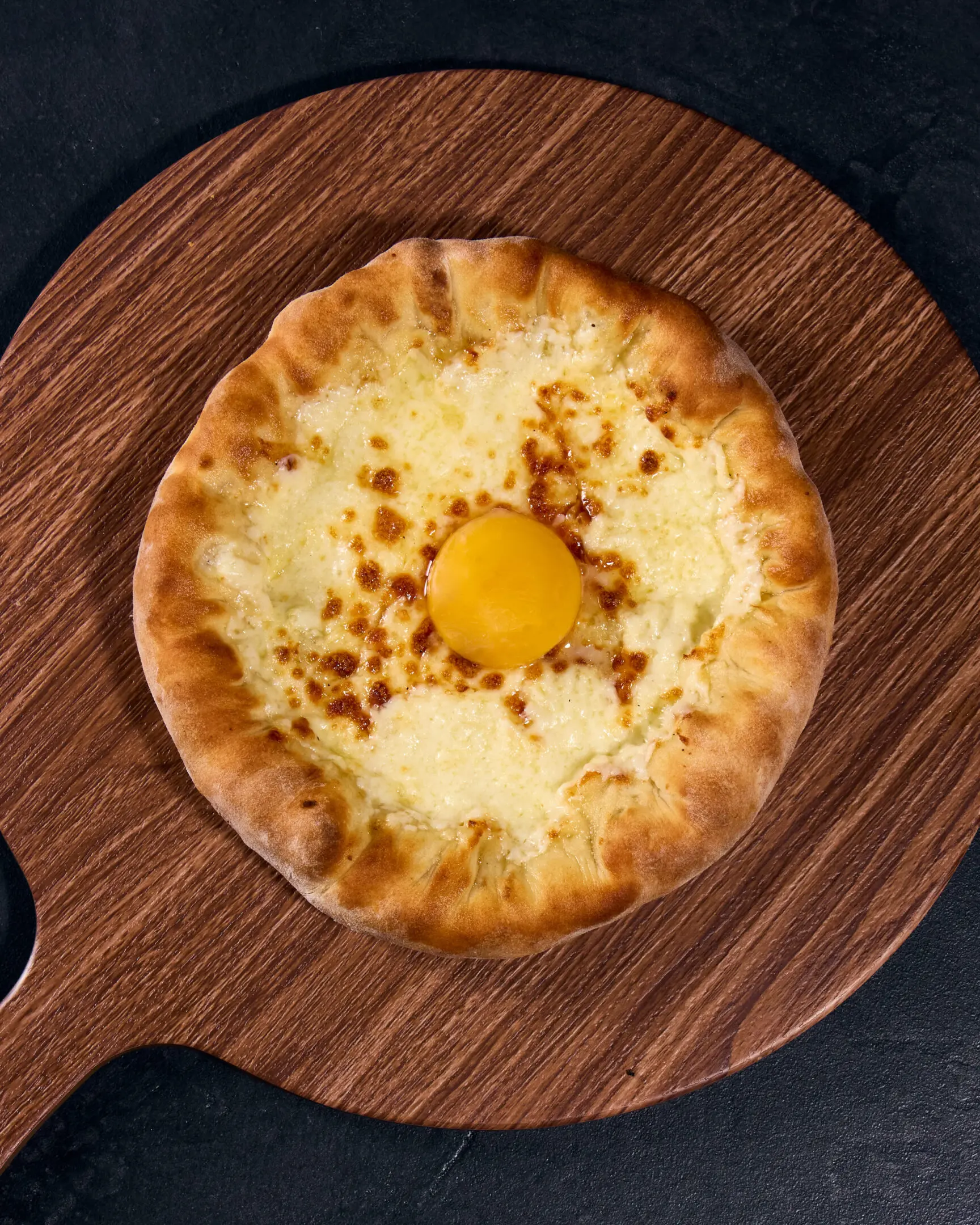Cheese bread with egg on wooden board.