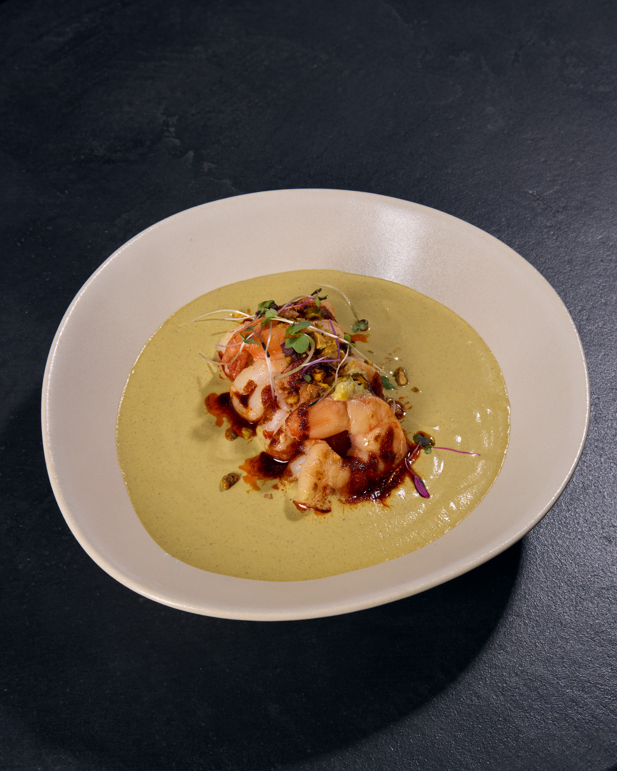 Creamy soup garnished with vegetables and herbs.